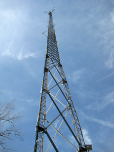 Top af a metal tower against blue sky and wispy clouds